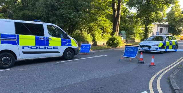 A police van and car blocking the road