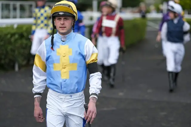 Jockey in blue and white clothing wearing a black armband on left arm