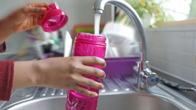 Someone filling up a water bottle from the tap