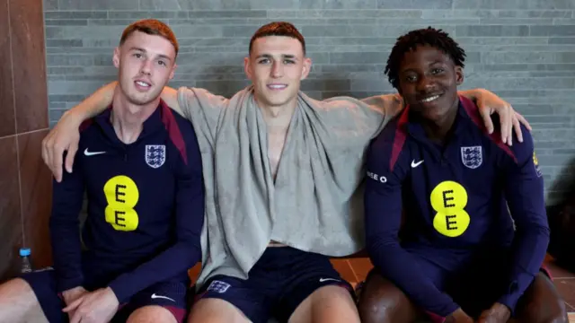 Cole Palmer sat posing for the camera with England team-mates Phil Foden and Kobbie Mainoo