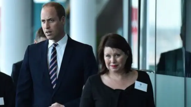 Julie Harrington with dark hair and wearing black top with name badge next to Prince William