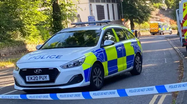 A police car with tape closing the road