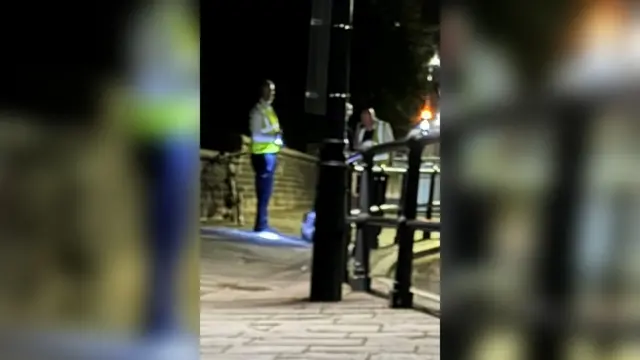 Suspension bridge toll guards wearing hi-vis clothing with pavement in foreground