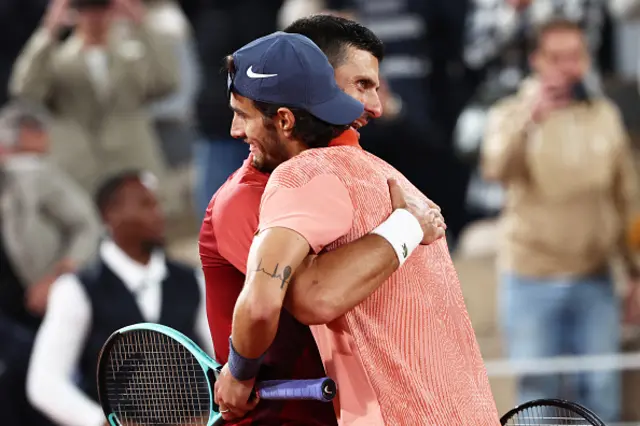 Serbia's Novak Djokovic (L) embraces with Italy's Lorenzo Musetti after winning at the end of their men's singles match on Court Philippe-Chatrier