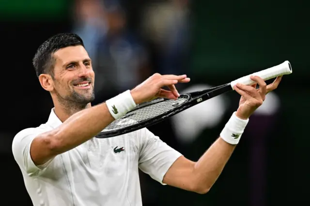 Novak Djokovic mimes playing a violin on his tennis racquet