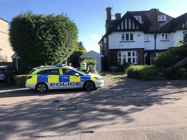 Three-storey Victorian house with police car outside and two police officers standing beside it