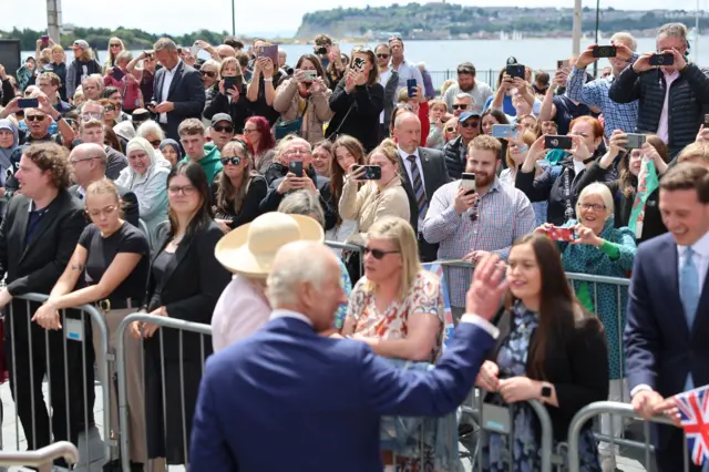 A picture of a crowd taking picture of the King and Queen