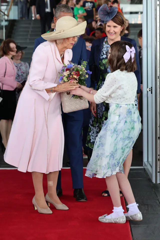 Queen meets a young girl who presents her with flowers