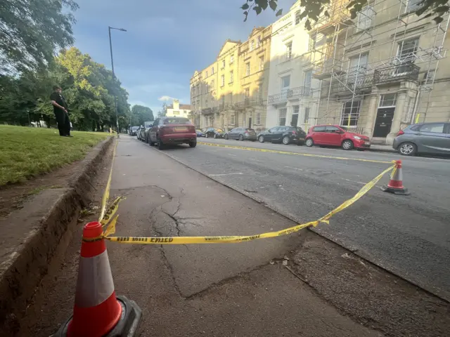 A cordon area marked with yellow tape attached to cones on a residential street