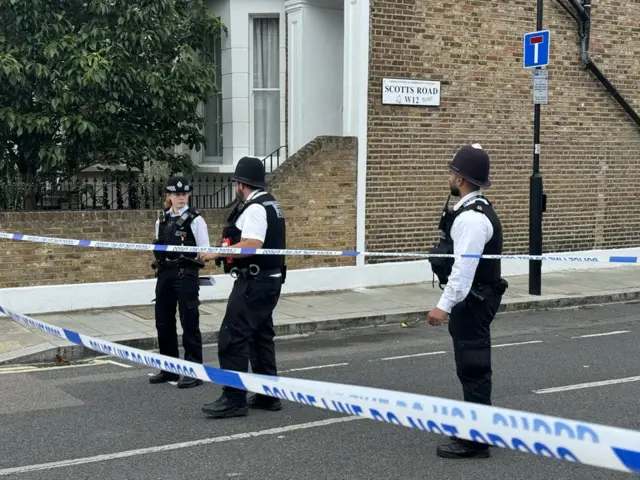 Three police officers standing in front of police tape