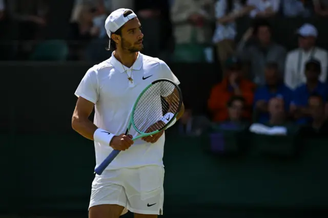 Luciano Musetti holds a tennis racquet