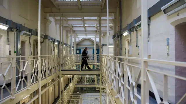 A prisoner officer walks the landing of Drake wing, HMP/YOI Portland, a resettlement prison with a capacity for 530 prisoners.