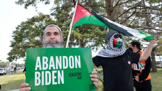 Voters hold an 'abandon Biden' sign