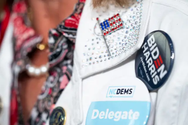 A woman wears a North Carolina delegate button during a campaign event with Vice President Kamala Harri