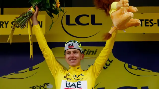 Tadej Pogacar holds his arms aloft on the podium after winning stage 14 of the 2024 Tour de France