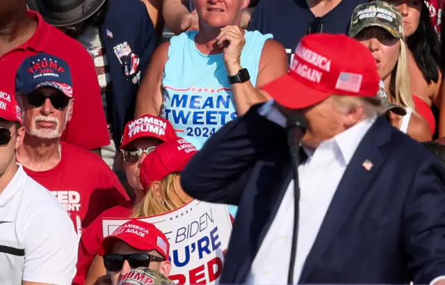 The moment loud pops ring out in the crowd at Donald Trump's rally in Pennsylvania. He appears to reach for his ear