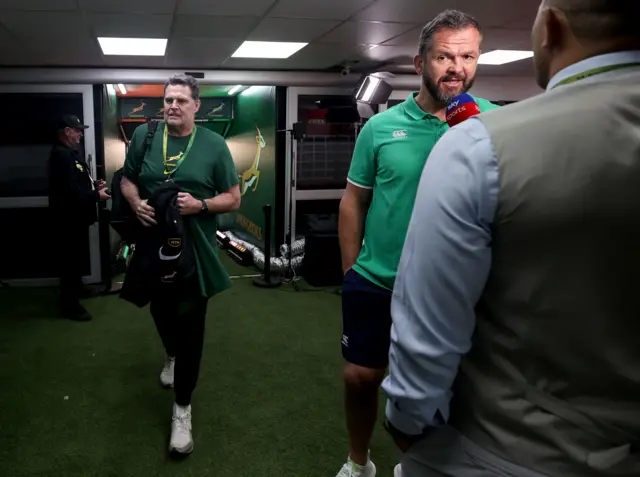 Rassie Erasmus arrives while Andy Farrell speaks to the media