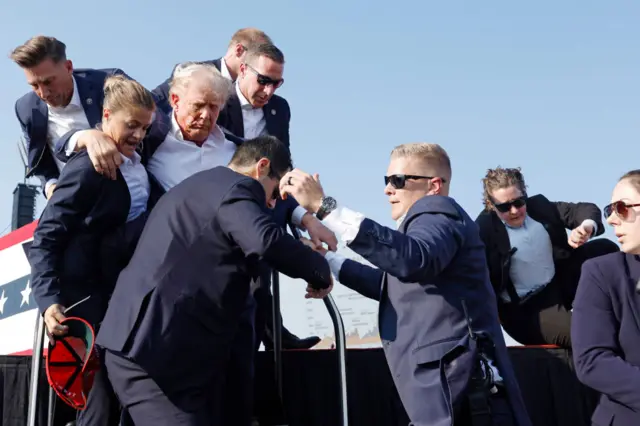 Donald Trump is escorted from the stage by Secret Service agents