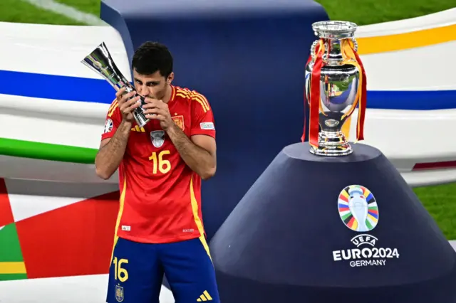 Rodri kisses his player of the tournament trophy