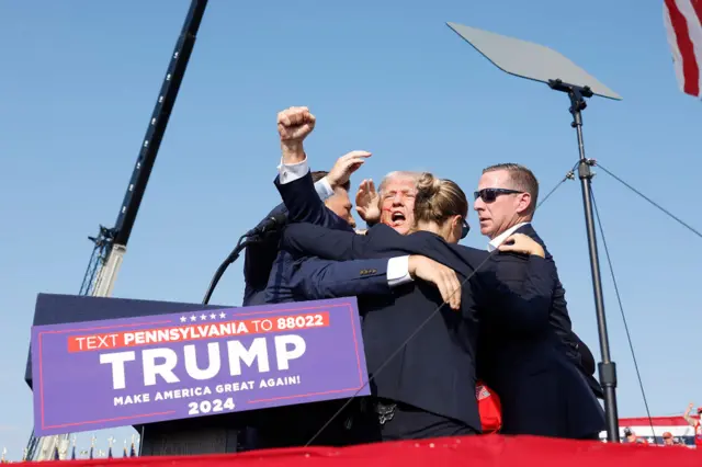 Trump raises a fist as he is surrounded by secret agents