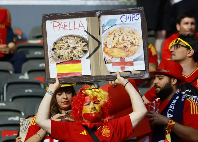 Fan holds up a Paella v Fish and Chips