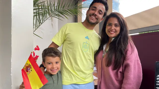 Gabriel, Roberto and Emily pose for a photograph with a Spain flag