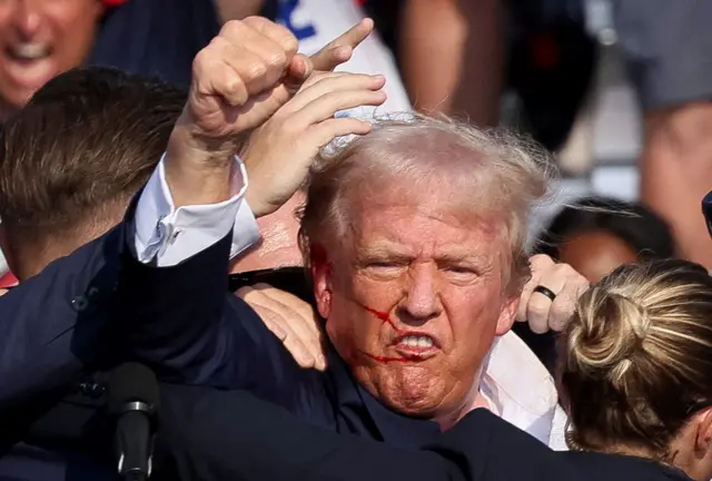 Trump is assisted by the Secret Service after gunfire rang out during a campaign rally at the Butler Farm Show in Butler, Pennsylvania