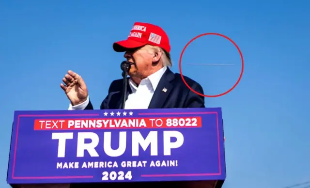 Donald Trump is pictured at the podium with a bullet grazing past him, circled in red