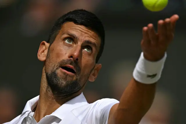 Novak Djokovic throws the ball to serve