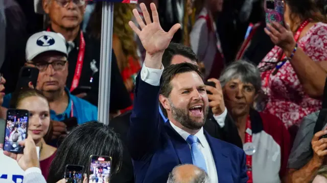 JD Vance holds up his hand to the crowd with a big smile