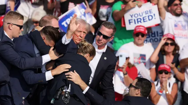 Donald Trump, with blood on his face, raises his fist in the air