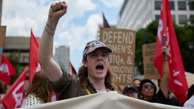 Man holds his fist in the air while standing in a march