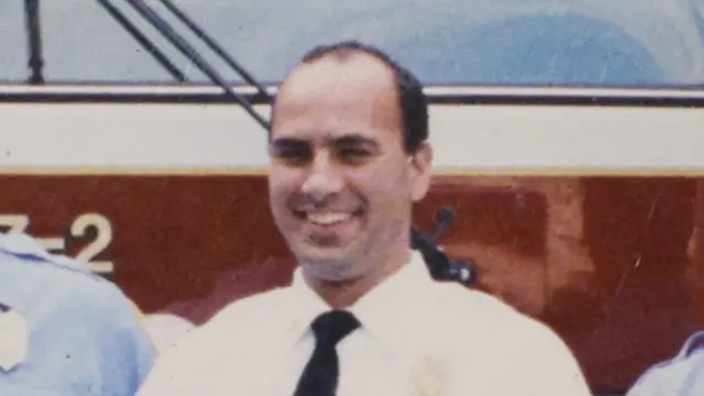 Corey Comperatore stands in front of a fire engine in an old photo of him in his uniform