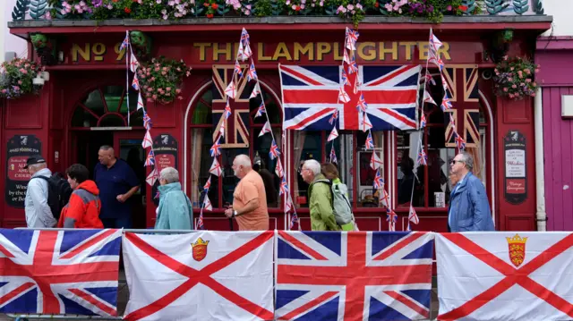 People walk past bunting outside the Lamplighter pub in St Helier, Jersey