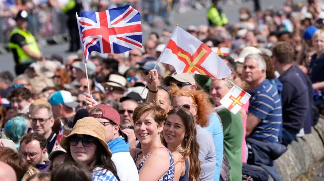 Crowds gather ahead of Charles III and Queen Camilla's arrival, to attend the special sitting of the States of Deliberation, at Guernsey Parliament at Saint Peter Port.