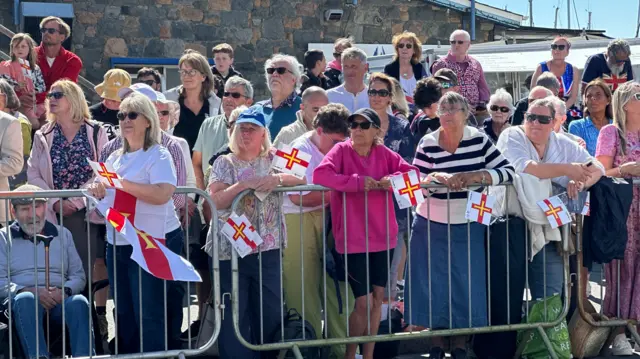 Lined barriers of islanders in Guernsey waiting for the King and Queen to arrive