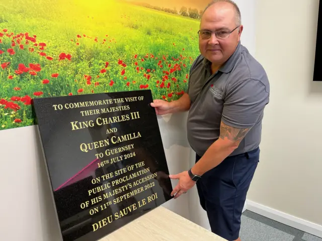 Man stood next to plaque