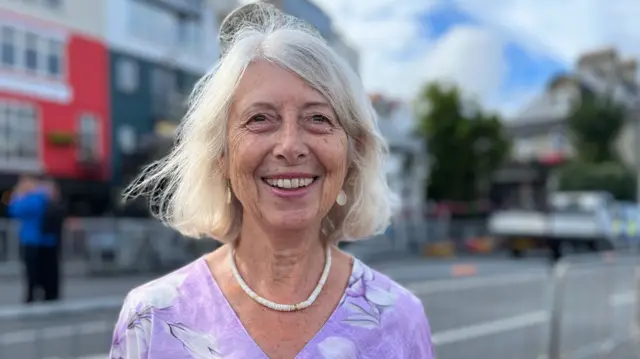 Smiling woman stood by barriers on St Peter Port seafront