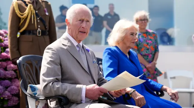 King Charles III makes a statement to members of the Alderney island with Queen Camilla, during a visit to Les Cotils