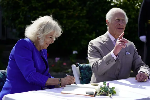 King Charles III and Queen Camilla sign a book during a visit to Les Cotils at L'Hyvreuse, in Saint Peter Port, Guernsey