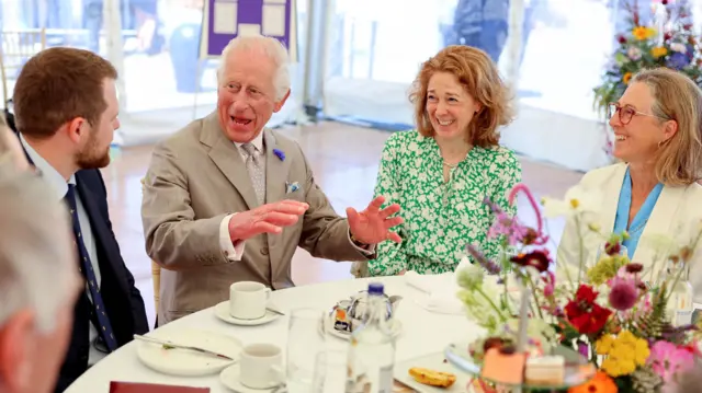 King Charles talking to a table of people at a tea party in Guernsey