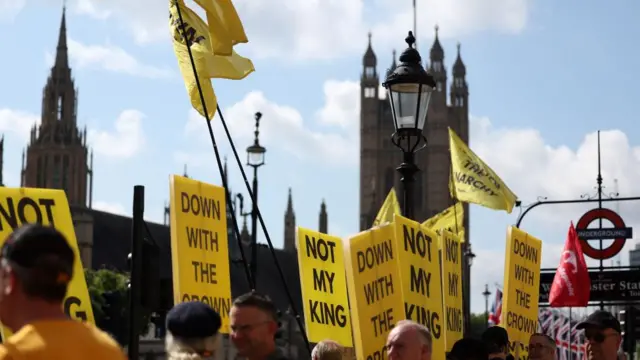 People hold placards as they take part in an anti-monarchy protest ahead the State Opening of Parliament