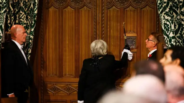 As part of the ceremony, Black Rod - a House of Lords post, currently held by Sarah Clarke - is initially denied entry to the House of Commons