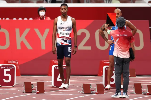 Zharnel Hughes is shown a red card on the starting blocks at the Tokyo 2020 Olympics