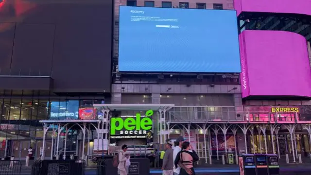 A billboard above a line of shops showing the "blue screen of death".