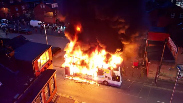 Double decker bus on fire shot from a drone