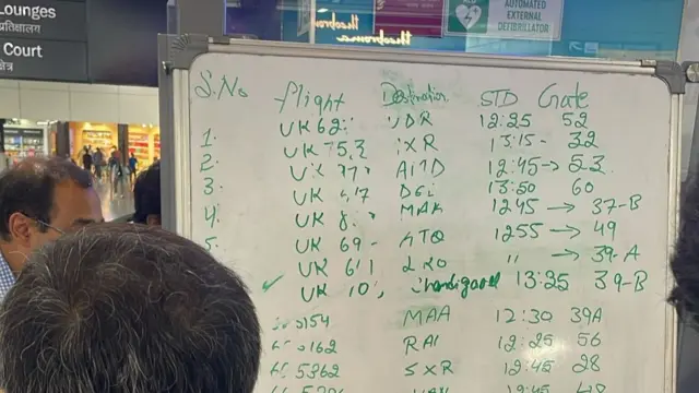 A whiteboard showing departure times at the international airport in Delhi