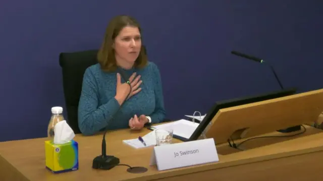 Jo Swinson speaks at the inquiry with her hand on her chest.