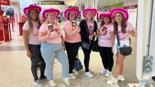 Six women in matching pink t-shirts and hats