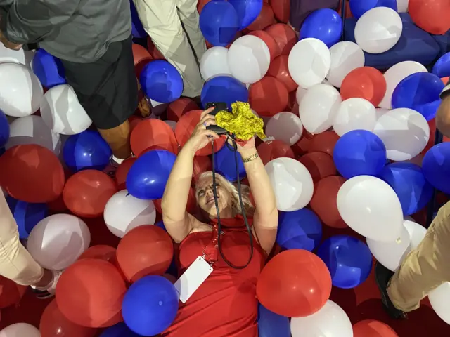 Woman lies among balloons.